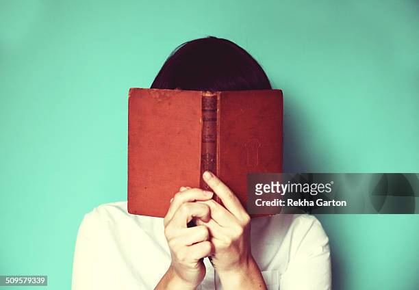 woman's holding a book in front of her face - femme visage caché photos et images de collection