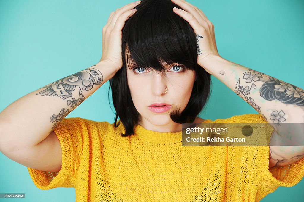 Young woman with tattoos holding her head