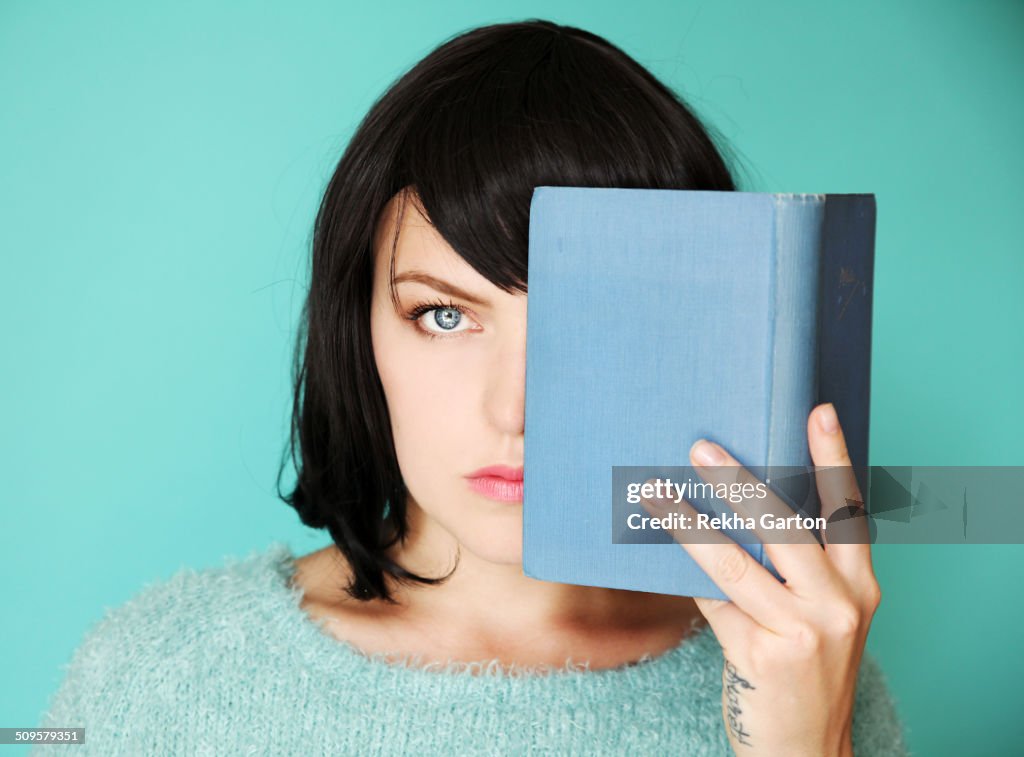 Half a woman's face covered with a blue book