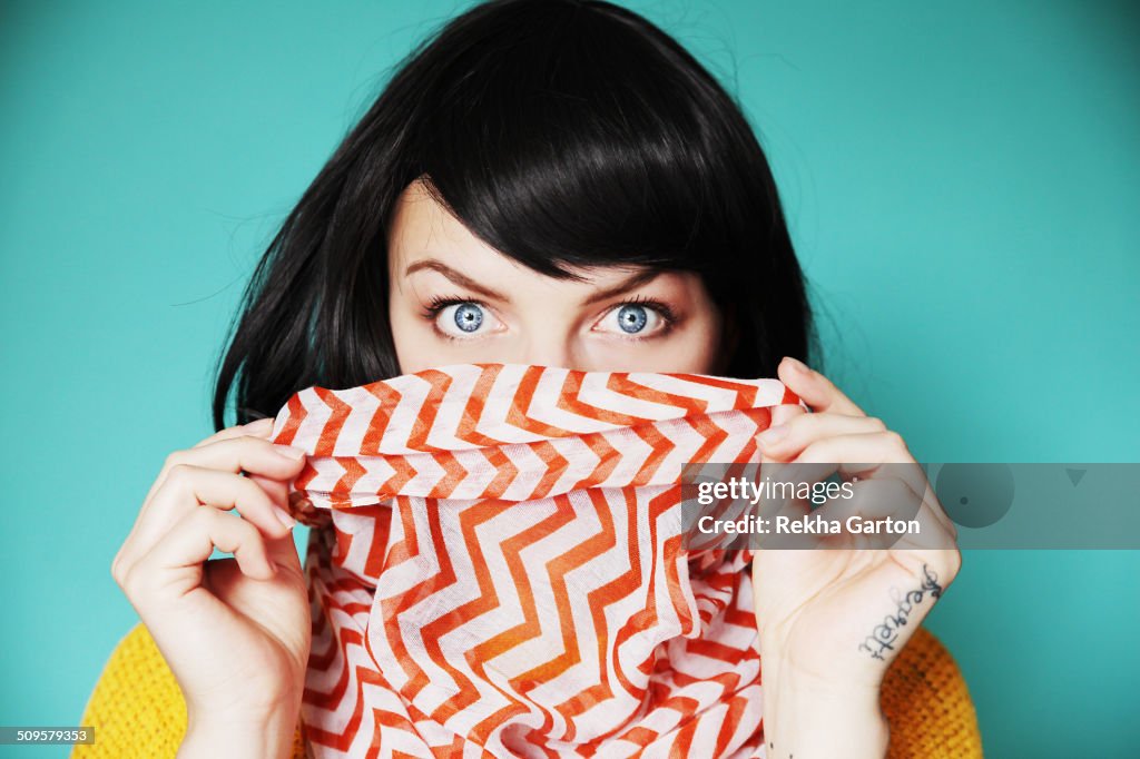 Woman holding bright scarf over lips with shock