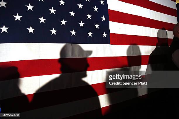 Shadows are reflected on an American Flag as people line up to speak with Ohio Governor and Republican presidential candidate John Kasich at a...