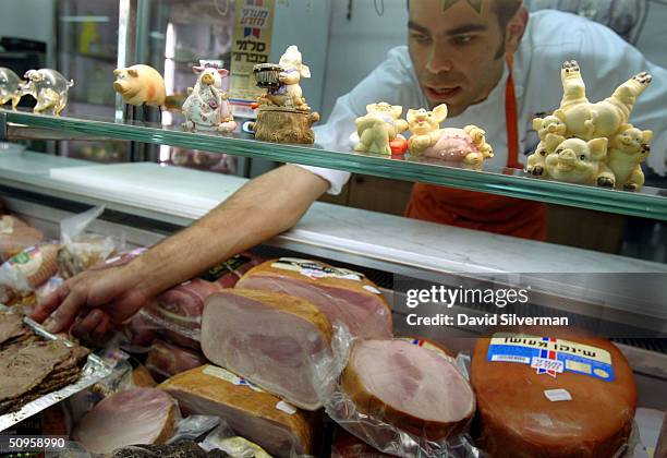 Israeli butcher Ronen Solomon arranges a display of non-kosher meats in his delicatessen June 14, 2004 in Ranana in central Israel. Israel's High...