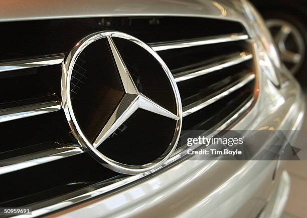 The three-pointed star, Mercedes-Benz emblem is seen on the grille of a sedan in the showroom of Mercedes-Benz of Hoffman Estates June 14, 2004 in...