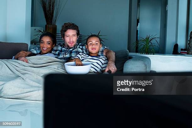 family having popcorn while watching tv - tv family stockfoto's en -beelden