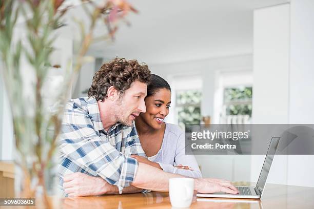 couple using laptop at home - couple looking laptop foto e immagini stock