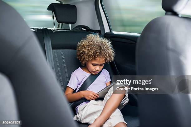 girl using digital tablet in car - rücksitz stock-fotos und bilder