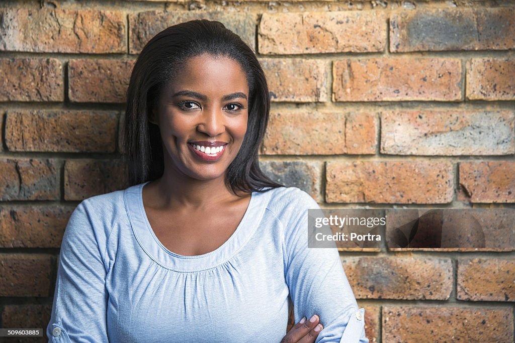 Happy woman against brick wall