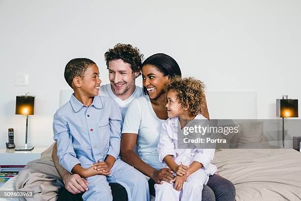 happy family sitting on bed - family with two children stock pictures, royalty-free photos & images
