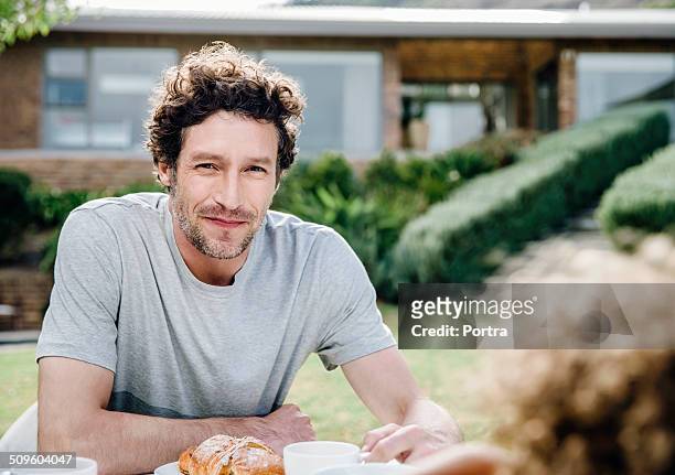 happy man having breakfast at outdoor table - hair stubble stock-fotos und bilder