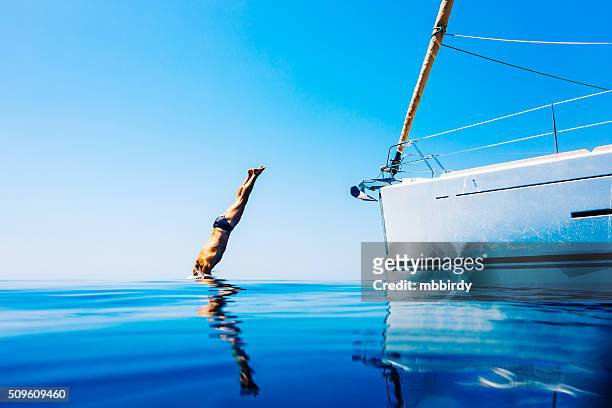 homme de sauter dans la mer depuis un bateau à voile - jumping of boat photos et images de collection