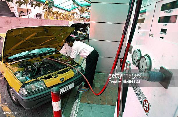 Taxi driver fills his car with Liquified Natural Gas at a gas station in Kuala Lumpur, 15 June 2004. LNG could become the fuel of choice for power...