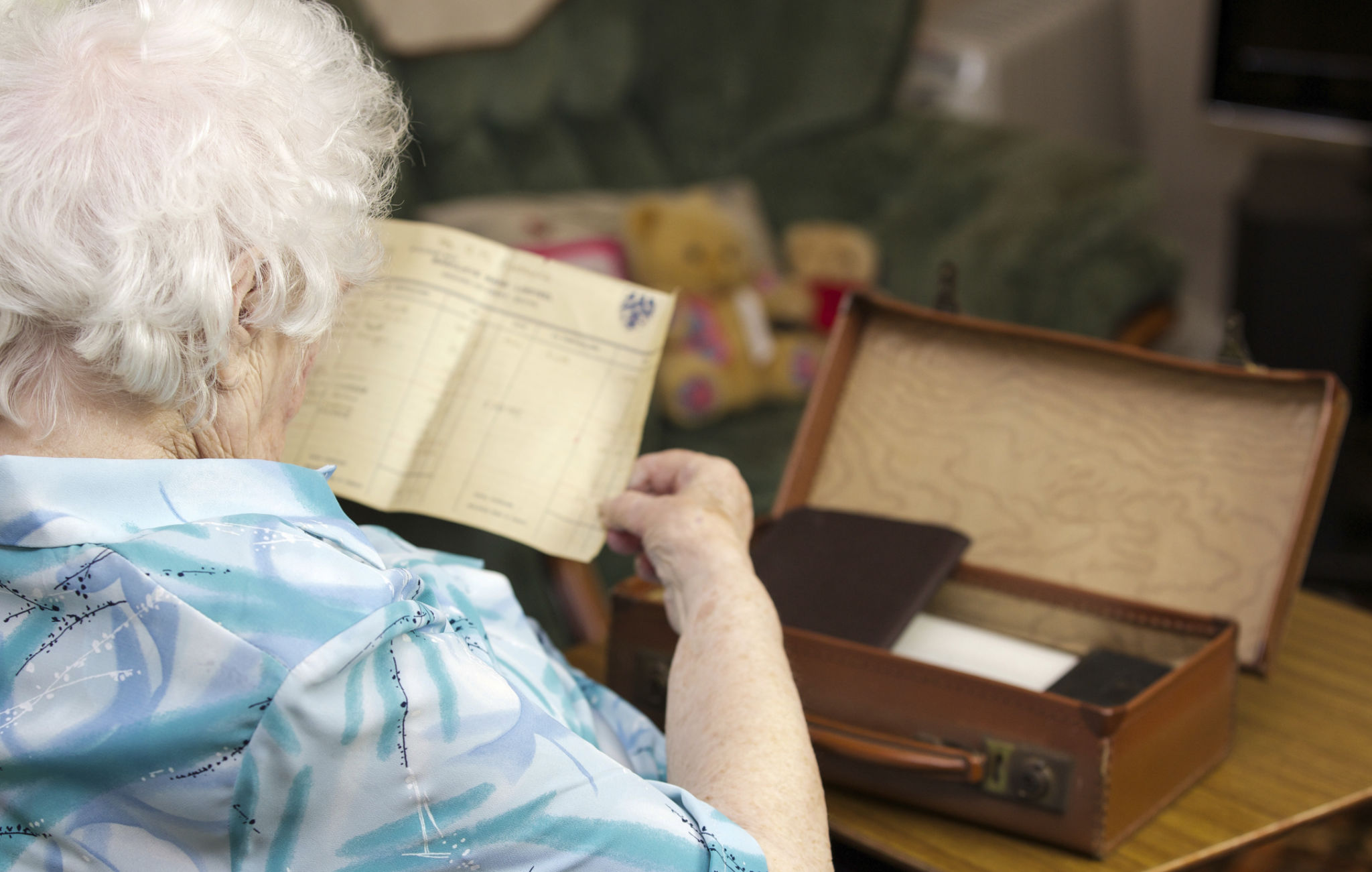 Elderly woman looking at old documents in a leather case Elderly woman looking at old documents in a leather case