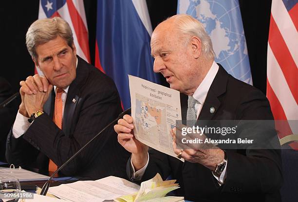 Secretary of State John Kerry listens to UN special envoy on Syria Staffan de Mistura holding up a map during a press conference following a meeting...
