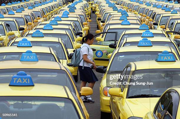 School girl walks through rows of taxis parked on a road on June 16 2004 in Seoul South Korea. Taxi drivers and metal workers went on strike to...