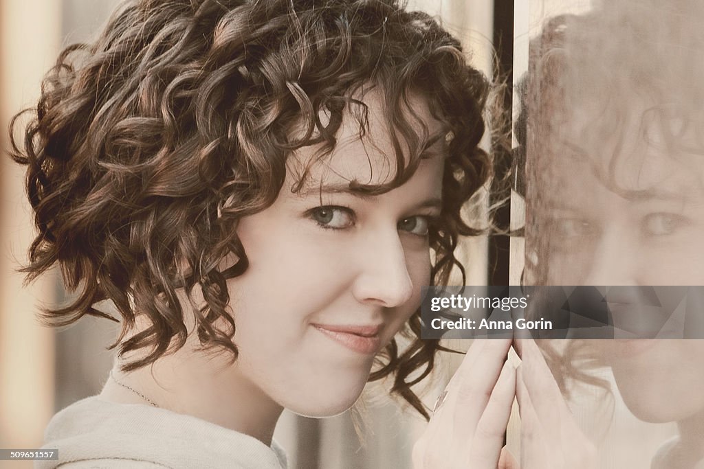 Young woman smiling and reflection in outdoor wall