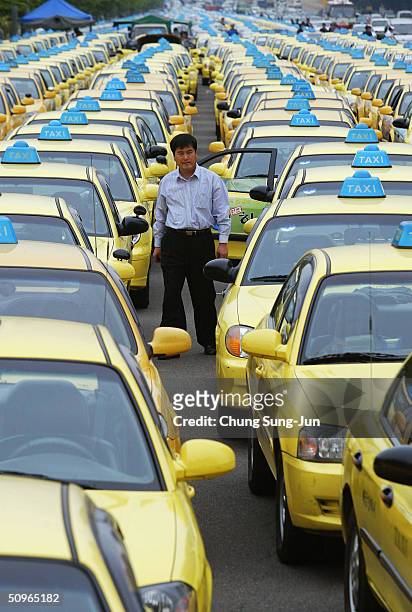 Taxi driver stands amongst rows of taxis as they block a road on June 16 2004 in Seoul South Korea. Taxi drivers and metal workers went on strike to...