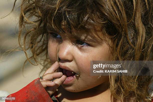 Ghagar or gypsy child with flies on her face is seen outside her home near a garbage dump in Taji, some 10 kms north of Baghdad 16 June 2004. Around...