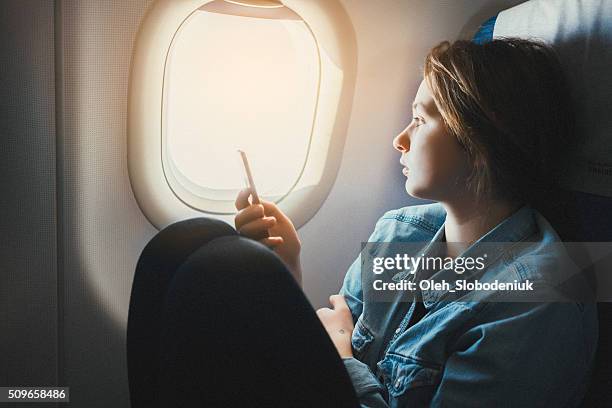 woman with smartphone in airplane - patrijspoort stockfoto's en -beelden