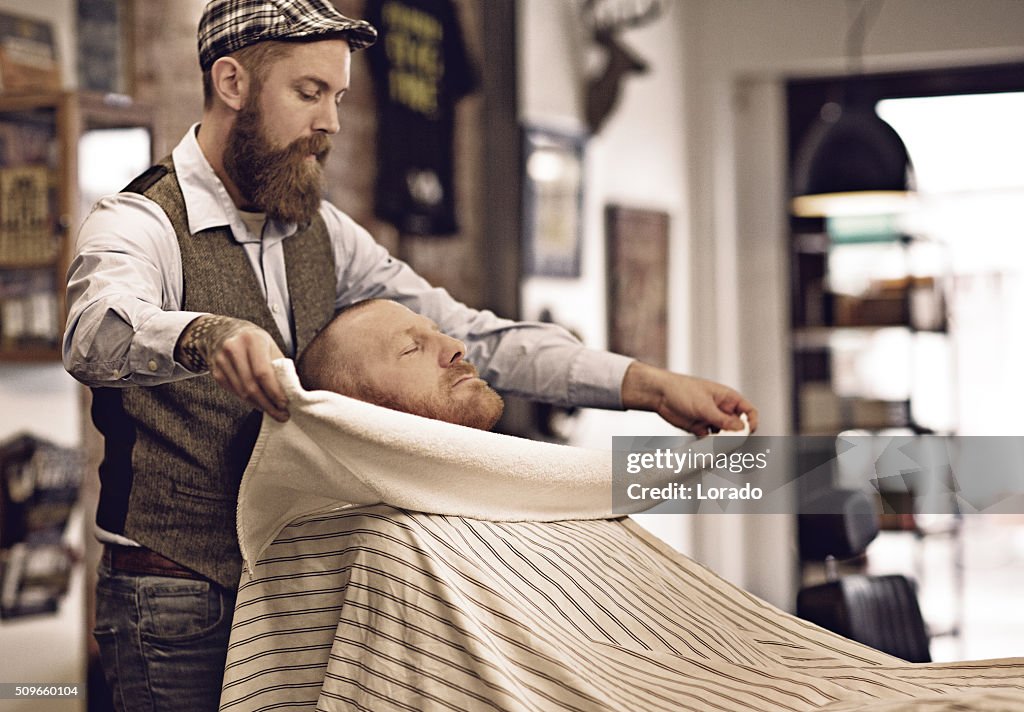 Stylish retro bearded barber with a bearded bald male client