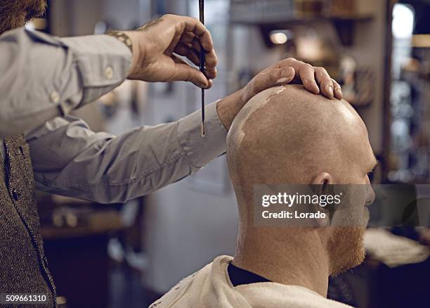 un elegante vintage barbiere rasatura di un cliente di un uomo calvo - bald man foto e immagini stock