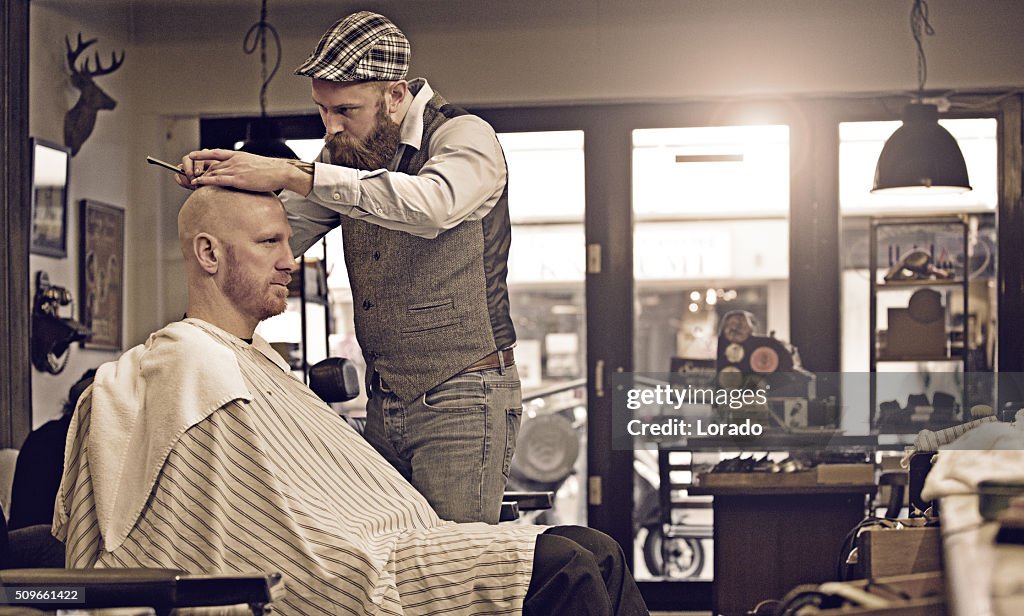 Stilvoller retro-bärtiger Friseur mit einem bärtigen männlichen Kunden Glatze