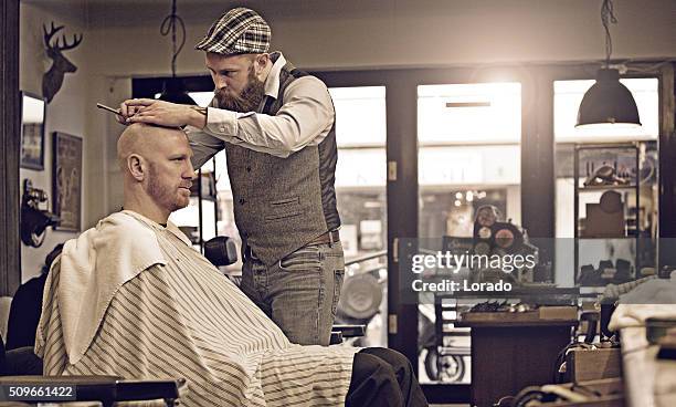 stylish retro bearded barber with a bearded bald male client - shaved head profile stock pictures, royalty-free photos & images