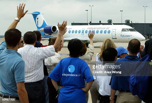 Guests wave as an inbound Independence Air plane lands June 16, 2004 during a launching ceremony at Dulles Airport in Virginia outside Washington,...