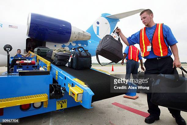 Ground crew member Richard Woodruff loads passengers' luggage onto an Independence Air plane at Dulles Airport on June 16, 2004 in Virginia, located...