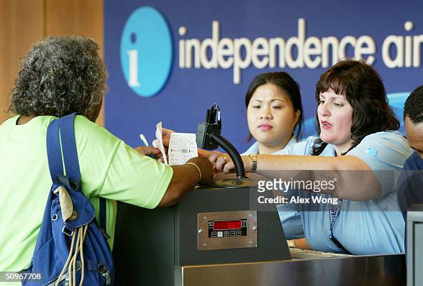 Independence Air customer service agents Karen Dacey and Peggy Ticoalu serve a passenger at the airline's ticketing counters June 16, 2004 at Dulles...