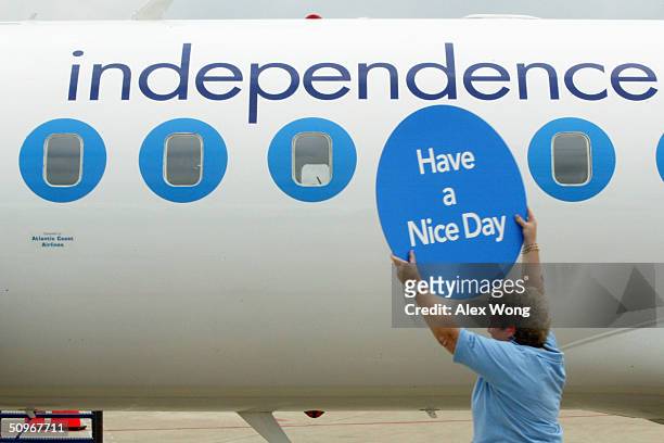 Independence Air Safety Manager Sue Leferson greets on-board passengers with a placard June 16, 2004 at Dulles Airport in Virginia outside...