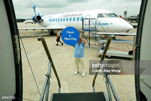 Independence Air Safety Manager Sue Leferson greets on-board passengers with a placard June 16, 2004 at Dulles Airport in Virginia outside...
