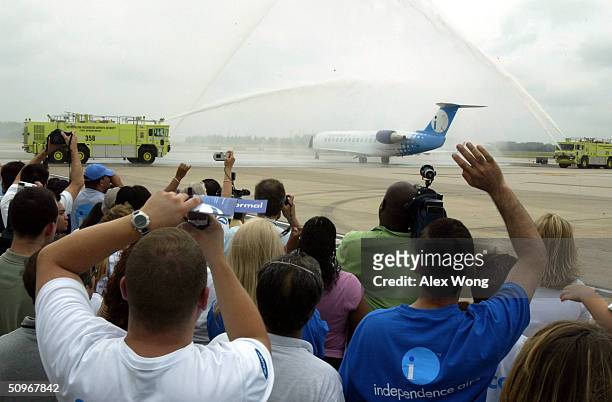 Guests celebrate as a water cannon salute greets an Independence Air outbound plane June 16, 2004 at Dulles Airport in Virginia outside Washington,...