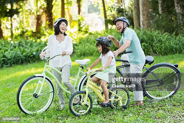 little girl riding bicycles with grandparents - asian cycling stock pictures, royalty-free photos & images