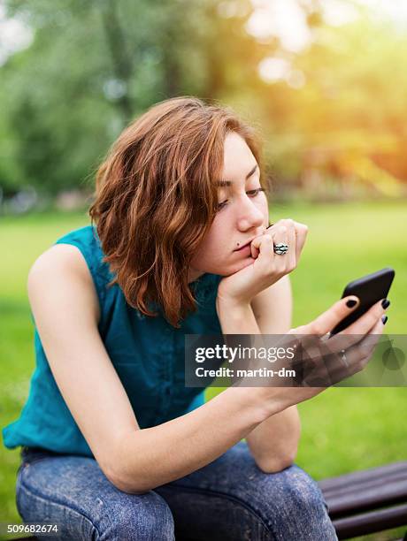 teenage girl texting on smartphone in the park - child waiting stock pictures, royalty-free photos & images