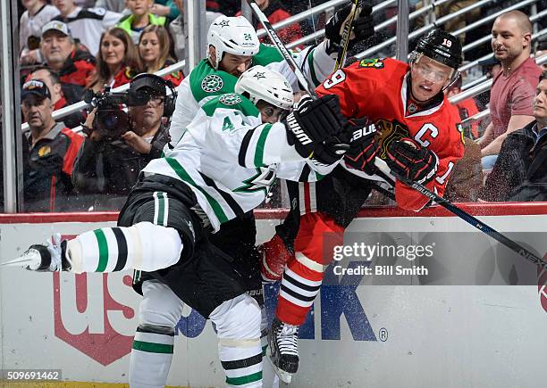 Jonathan Toews of the Chicago Blackhawks takes a hit by Johnny Oduya and Jordie Benn of the Dallas Stars in the third period of the NHL game at the...