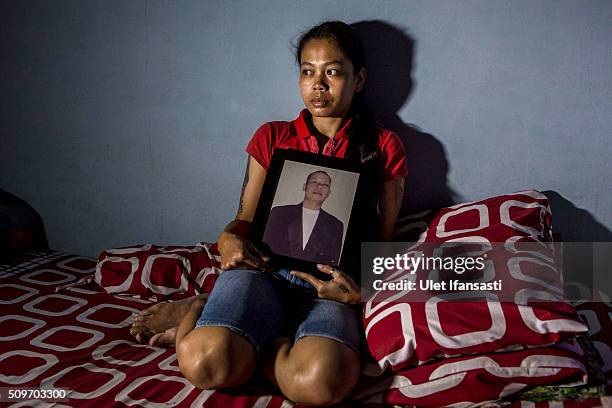 Fransiska Wulandari, 30 holds a photo of her husband, Donny Tamtomo S, who died after drinking illegal alcohol known as 'oplosan,' on February 9,...