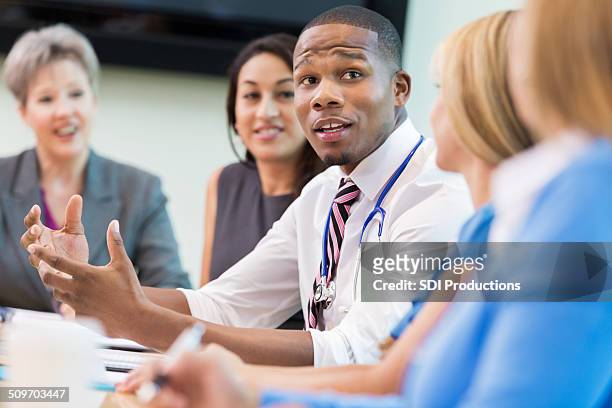 doctor talking with hospital board members during meeting - organised group stock pictures, royalty-free photos & images