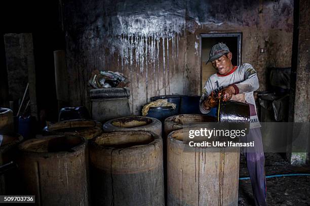 Worker fills drums with sugarcane fermentation during the distillation process of ethanol alcohol at Bekonang village on February 9, 2016 in...