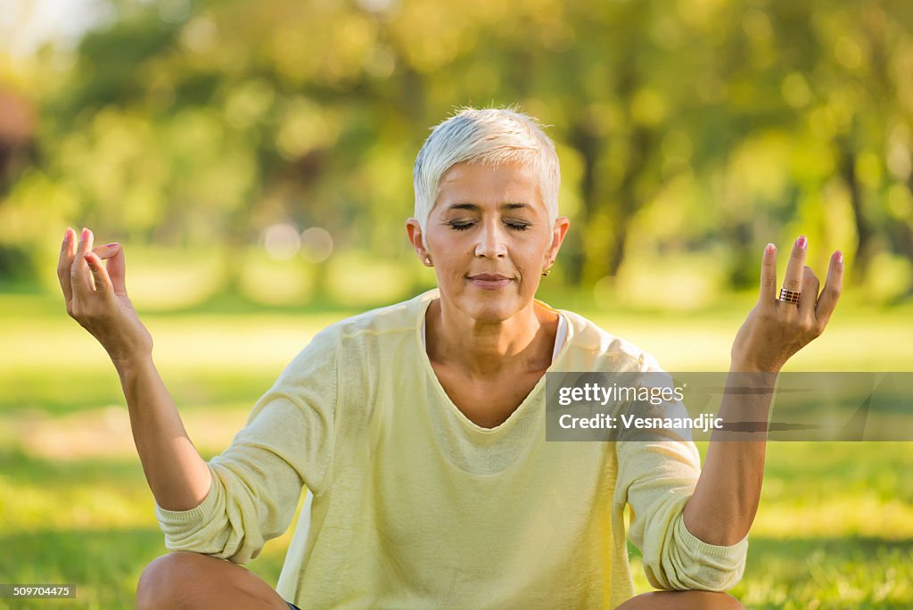 Mature women practising yoga in the meadow