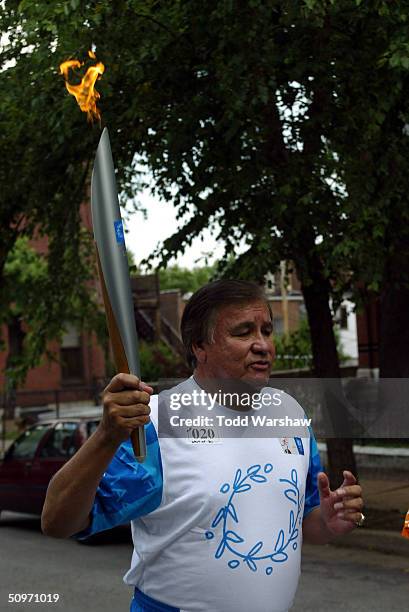 Olympian Billy Mills carries the Olympic Flame during Day 13 of the ATHENS 2004 Olympic Torch Relay June 17, 2004 in St. Louis, Missouri. The Olympic...