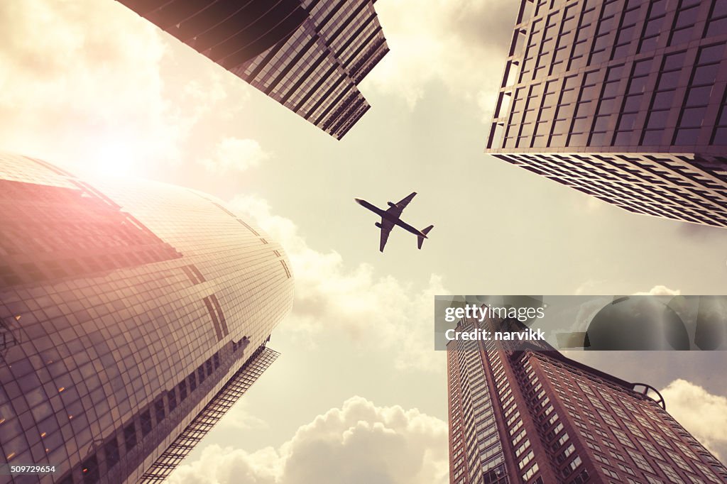 Airplane flying above skyscrapers