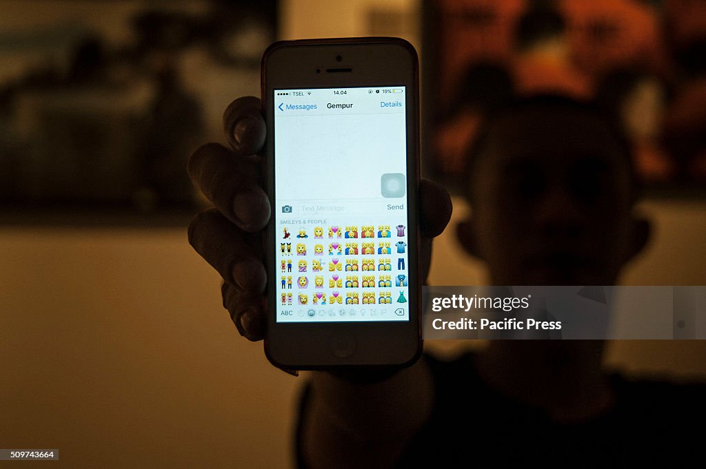 An Indonesian man holds his mobile phone showing the...