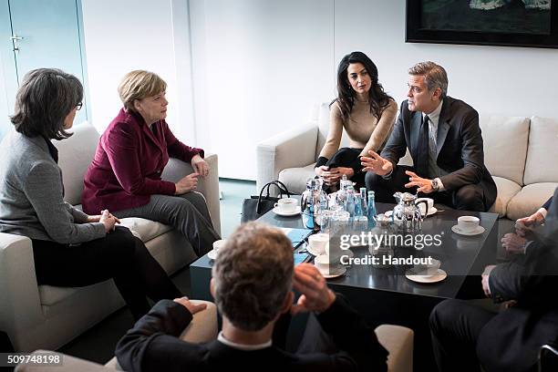 In this handout photo provided by the German Government Press Office Chancellor Angela Merkel meets with George Clooney and Amal Clooney at the...