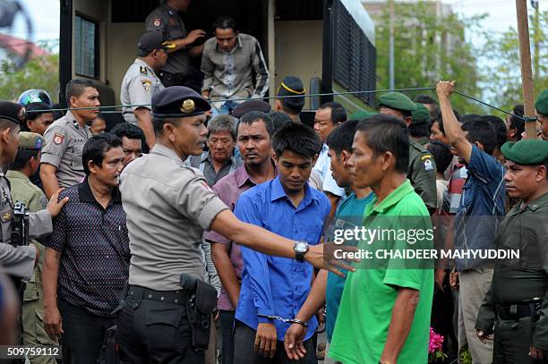Indonesian policemen escort 36 prisoners before they are whipped during a public caning Sharia Law punishment at a Mosque in Meulaboh on the west...