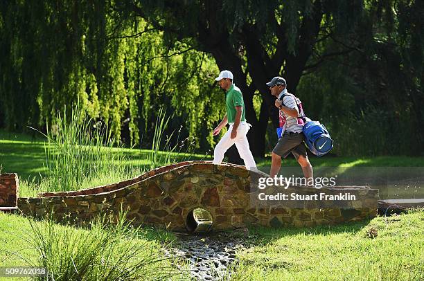 Charl Schwartzel of South Africa and caddie walk over a bridge during the second round of the Tshwane Open at Pretoria Country Club on February 12,...