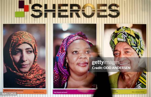 Woman walks past portraits of the 2011 Nobel Peace Prize laureates from right to left, Liberian President Ellen Johnson Sirleaf, Liberia "peace...