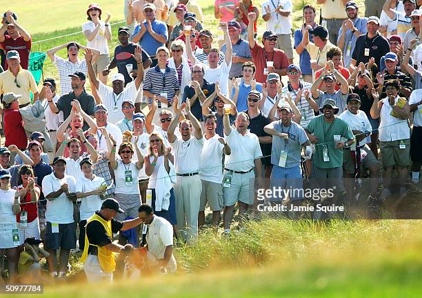 The crowd cheers Tiger Woods as his caddie Steve Williams congratulates him after Woods made an eagle on the 18th hole during the third round of the...