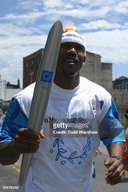 Torchbearer and NBA player from the New York Knicks Stephon Marbury carries the Olympic Flame during Day 15 of the ATHENS 2004 Olympic Torch Relay on...