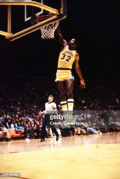 American basketball player Magic Johnson , of the Los Angeles Lakers, dunks the ball during a game, September 1982.