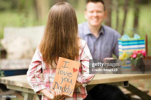 daughter gives dad handmade father's day card. outdoors. child, parent. - blank greeting card stockfoto's en -beelden